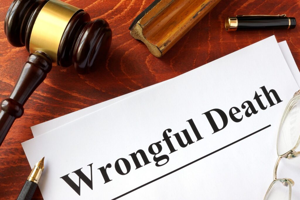 paper with wrongful death surrounded by gavel, pen, glasses- all on a wrongful death attorney's death