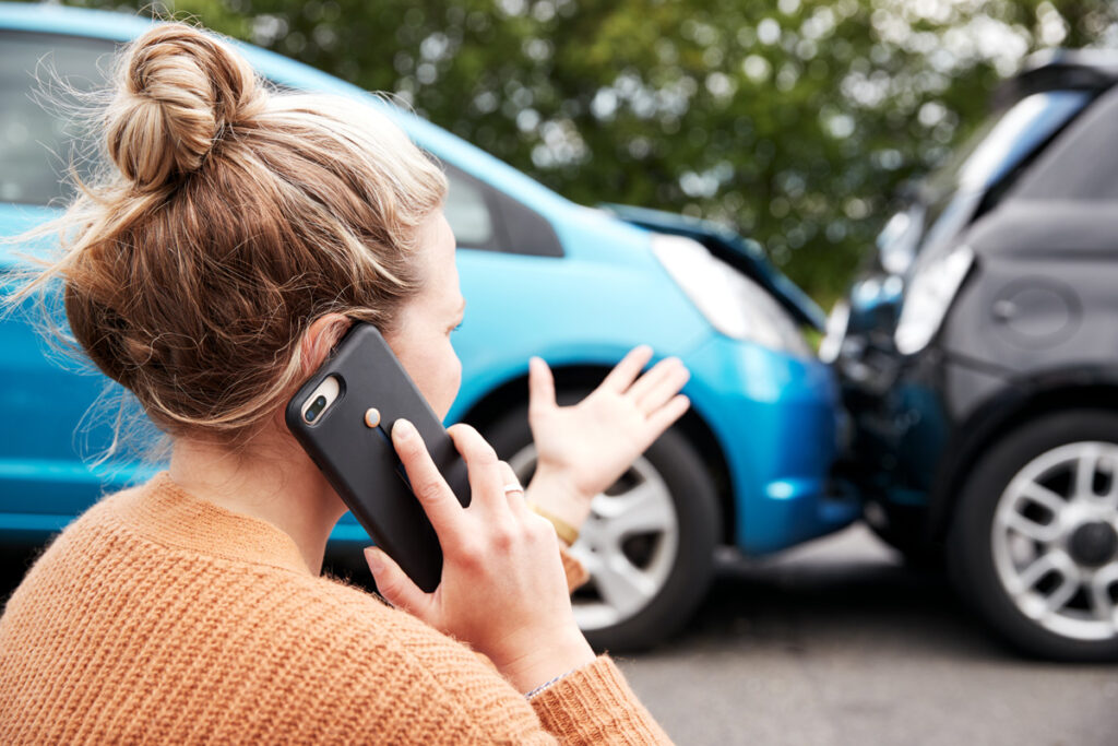 Woman consulting El Paso Personal injury attorney over the phone at the scene of a car accident.