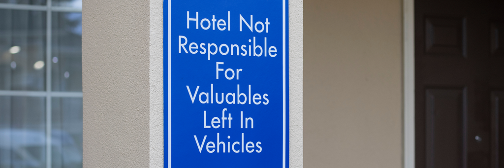 "Hotel Not Responsible For Valuables Left in Vehicles" disclaimer sign posted at a hotel's parking lot.