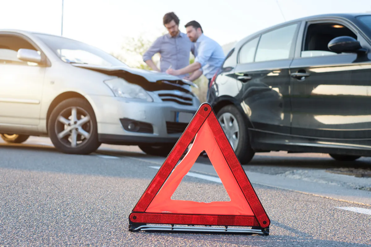 Two men looking at their damaged vehicles with a red caution sign in front in El Paso.