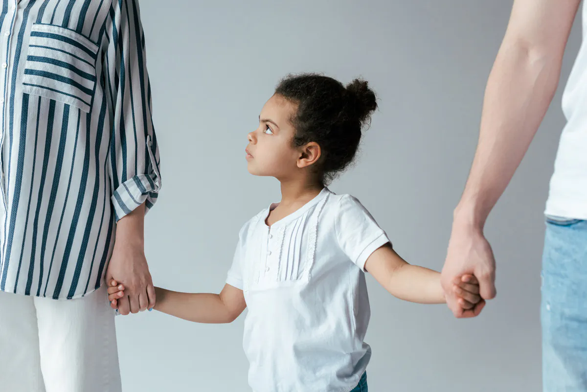 A child holding hands with two parents in El Paso.